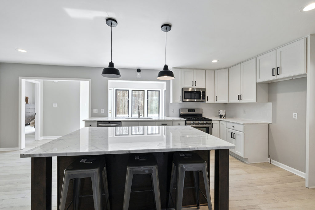 white kitchen with black island and pendant lights